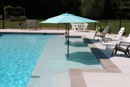 Large sun shelf beside the rectangular pool with two shade umbrellas