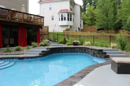 Triangle project freeform pool with raised stone-faced wall and entry steps