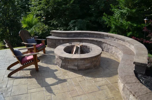 Stone fire pit with curved seating wall beside the pool