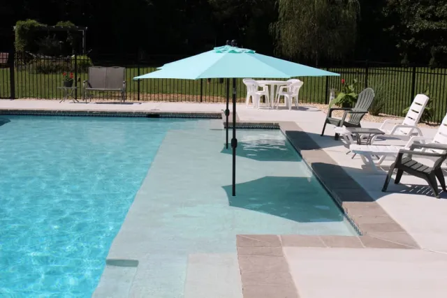 Large sun shelf beside the rectangular pool with two shade umbrellas