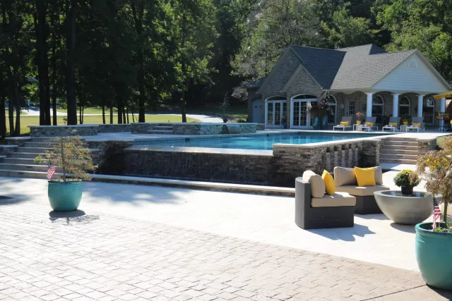 Thorny Point infinity pool with a stone-faced weir wall and paved seating area