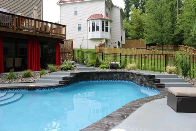 Triangle project freeform pool with raised stone-faced wall and entry steps