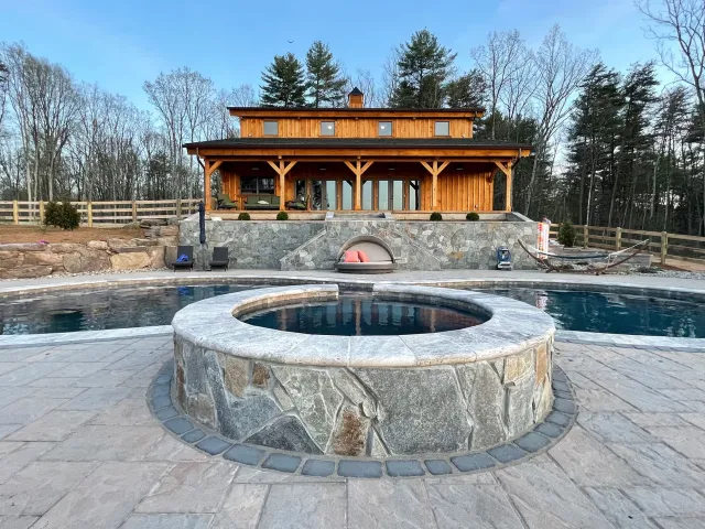 Round stone-faced Olsen-Locust Grove spa beside the curved swimming pool