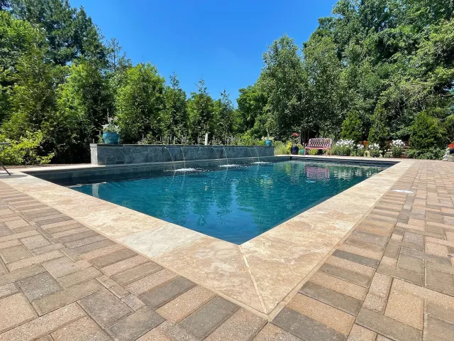 Angled view of the Lipman-Herndon pool edge, patio paving and water-feature wall