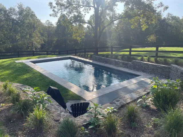 Rizzo-Madison rectangular pool beside lawn, planting and stone-faced wall