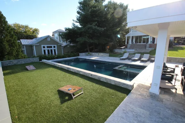 Haynes-Fredericksburg pool with raised water-feature wall beside the lawn